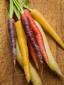 Multi-colored carrots in white, yellow, orange and red on a worn cutting board