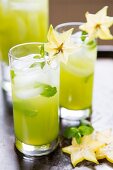 Two cocktails garnished with star fruit and peppermint