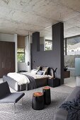 Elegant, purist, designer bedroom with dark grey partition, view into ensuite bathroom with panoramic windows and continuous concrete ceiling