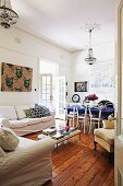 Sofa set with white loose covers, minimalist coffee table, rustic wooden floor and white Thonet chairs in dining area