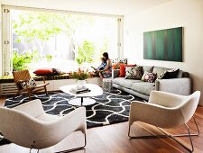 Light-flooded living room with open glass wall and mother and son sitting on window seat