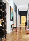 Golden, illuminated door at end of long hallway in Viennese period apartment; Chinese screen in foreground to one side