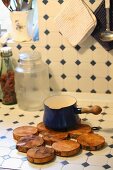 Trivet made from discs of wood on kitchen counter tiled in vintage pattern