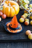 A Halloween hat in front of ornamental pumpkins and apples