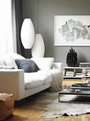Corner of modern, grey-painted living room with white sofa and cushions, classic Bubble Cigar pendant lamps and modern artwork on wall