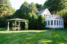 Pergola and whitewashed house with roof terrace on conservatory extension in large garden