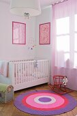 Kleinkinderzimmer mit gerahmten Musterbildern über weißem Gitterbett; Schaukelpferd auf rundem Teppich in violetten Tönen