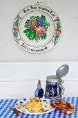 Obatzda (Barbarian cheese spread) with a pretzel, a tankard and a snuff bottle underneath an old fashioned painted plate hanging on a wall