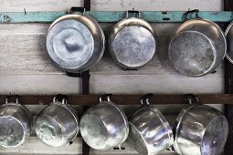 Metal pots hanging on a wooden wall