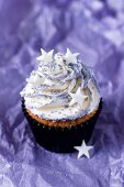 A cupcake topped with vanilla cream and decorated with stars