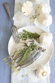 Raw sardines on a plate with thyme and garlic