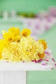 Daffodils and yellow carnations against green background