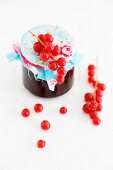 A jar on redcurrant jam with a fabric-covered lid