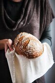 A woman holding a loaf of bread on a cloth