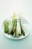 Green and white and wild asparagus bundled together on a plate