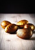 Mehrere goldene Schokoladenostereier auf Holzuntergrund