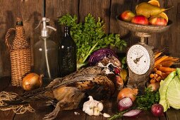 An autumnal arrangement featuring pheasant, vegetables, fruit, nuts and an old pair of kitchen scales