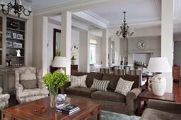 Offener eleganter Wohnraum im Landhausstil mit Stützen - Sitzbereich mit Polstermöbeln, Essplatz und offene Küche im Hintergrund