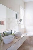 Bright modern bathroom with twin countertop basins on washstand with marble top