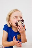 A little girl taking a big bite out of a chocolate marshmallow