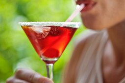 A woman drinking a red cocktail