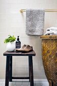 Rattan laundry basket next to antique shoe lasts and toiletries on vintage stool