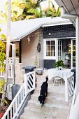 Dog on steps leading to furnished terrace of wooden house
