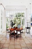 Dining area with chairs in a mixture of styles, tiled floor & floor-to-ceiling windows