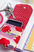 Open mobile phone pouch with pattern of apples on stack of books