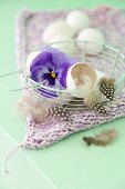 Egg shells, feathers and pansies in a wire basket