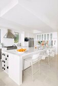 White glossy counter and designer bar stools in open-plan kitchen