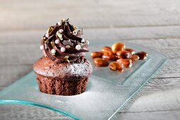 A chocolate cupcake decorated with sugar pearls and gold leaf