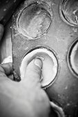 A hand pressing shortcrust pastry into a muffin tin (black-and-white image)
