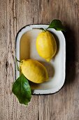 Two lemons with leaves in a bowl