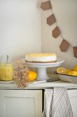 Lemon cheesecake with a bowl of fresh lemons and a jar of lemon cream next to it