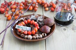A nametag with a wreath of rosehips, chestnuts and acorns on a brown plate