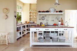 weiße Kücheninsel in offener Landhausküche mit sandfarbener Wand