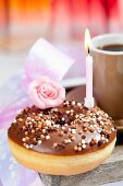 A doughnut with chocolate icing and a birthday candle