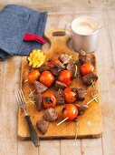 Grilled beef and tomato skewers on a wooden board