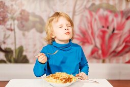 Junge isst Spaghetti mit Gabel