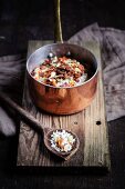 Risotto rice with a spice mixture made from dried tomatoes, herbs and garlic in a copper pot and on a wooden spoons