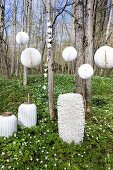 White lanterns of various shapes in thin woodland carpeted with flowering wood anemones