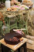 An autumnal buffet in a garden with a beetroot cake, rolls and a meat platter