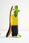 A bottle of vinegar and oil with basil and a wooden spoon