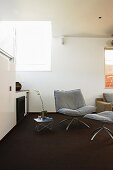 Armchair and matching footstool on dark carpet in minimalist interior