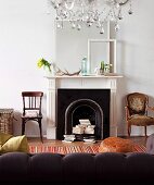 Books stacked casually in fireplace flanked by antique chairs & with shabby-chic ornaments on mantelpiece