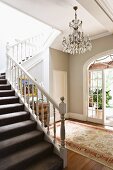 Open staircase, white carved wooden balustrade in grey-painted foyer of traditional country house