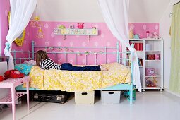Junges Mädchen auf Himmelbett mit weißem, drapiertem Vorhang, an Wand rosa Tapete mit Ornamentmuster