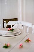 Roses and place setting on white wooden table and chair with name on backrest