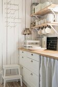 Detail of kitchen counter with wooden shelves of crockery and recipe written on white wooden wall
